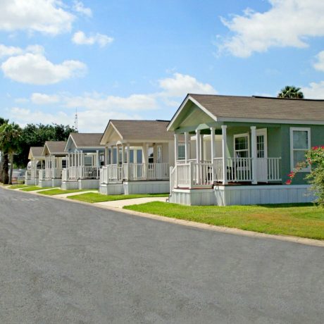 row of homes with porches and grassy lawns on a clear, sunny day